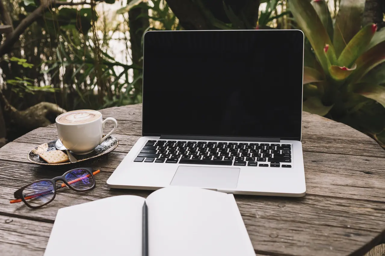 Młoda kobieta pracuje na lekkim laptopie siedząc w kawiarni, idealnym dla cyfrowych nomadów.