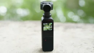 Bliska perspektywa rąk trzymających mały aparat cyfrowy i mikrofon, idealne jako kompaktowe urządzenia do vlogowania i nagrywania w podróży.