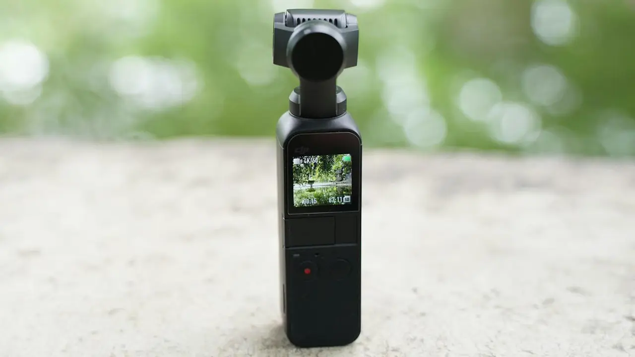 Bliska perspektywa rąk trzymających mały aparat cyfrowy i mikrofon, idealne jako kompaktowe urządzenia do vlogowania i nagrywania w podróży.