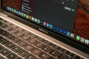 Dwa laptopy, MacBook i urządzenie z systemem Windows, leżące obok siebie na biurku, symbolizujące porównanie idealnego sprzętu dla studenta i twórcy.