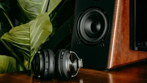 Nowoczesny zestaw audio z bezprzewodowymi słuchawkami i eleganckim głośnikiem, idealny do pracy zdalnej i wieczornego relaksu w domowym biurze.